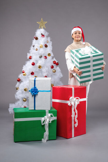 圣诞树年轻的女性在灰色的礼物购物长袜礼物