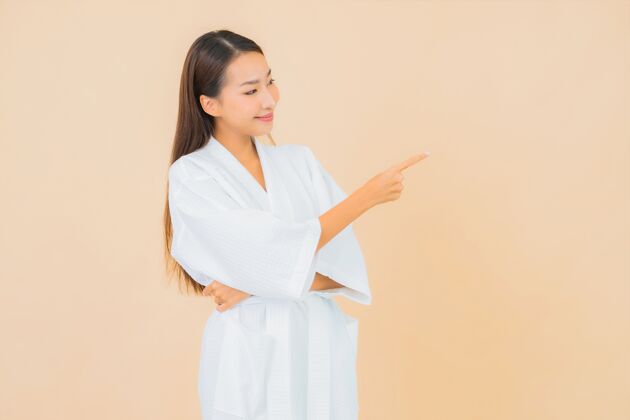 护理肖像美丽的亚洲年轻女子穿着米色的微笑浴袍诊所淋浴黑发