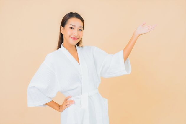 清洁肖像美丽的亚洲年轻女子穿着米色的微笑浴袍自然浴室女士