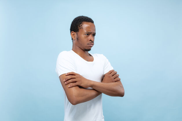 非洲人穿着白衬衫的非洲裔美国年轻人的特写肖像双手交叉站立 悲伤 沮丧或平静手男性人
