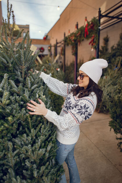 黑发优雅的女孩买了一棵圣诞树庆祝室内市场