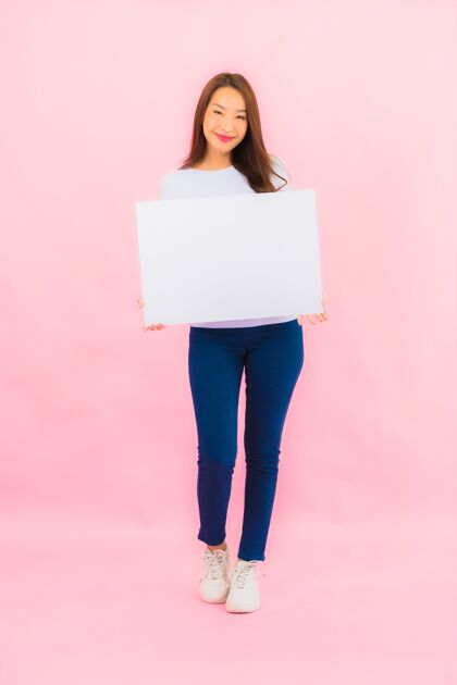 信息人像美丽的亚洲年轻女子在粉色墙上展示白色的文字广告牌日语白板空虚