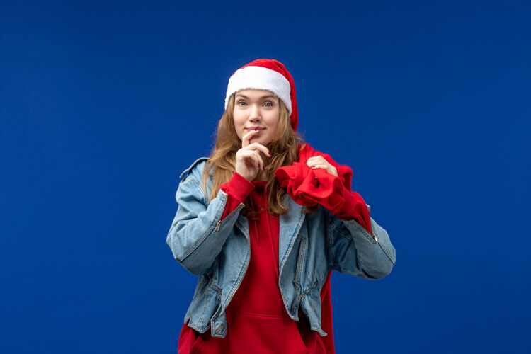 年轻女性正面图：年轻女性拎着装满礼物的袋子 蓝色书桌上的颜色感慨圣诞节年轻歌手蓝色