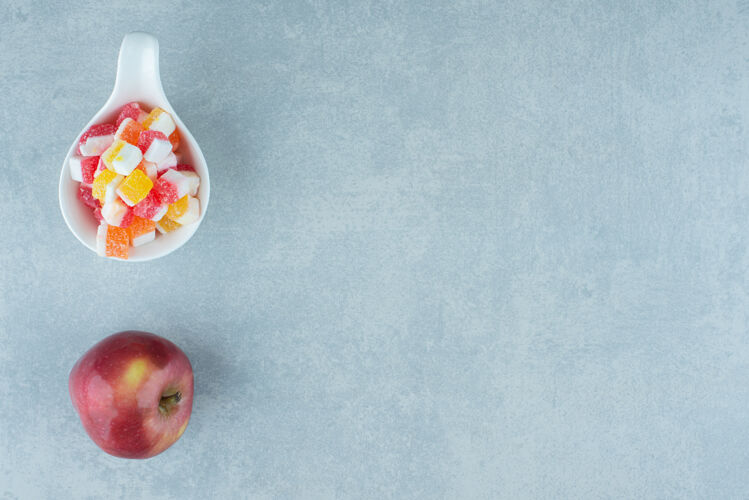 水果在大理石上放一个苹果和一小碗糖果糖营养视图