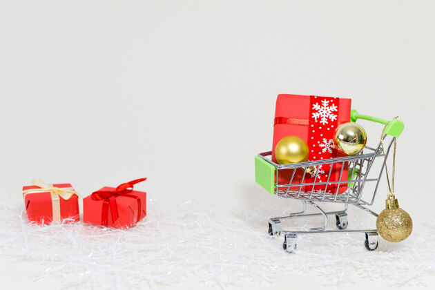 圣诞树购物手推车与礼品盒和金色球体上的雪花在白色的背景手推车背景球