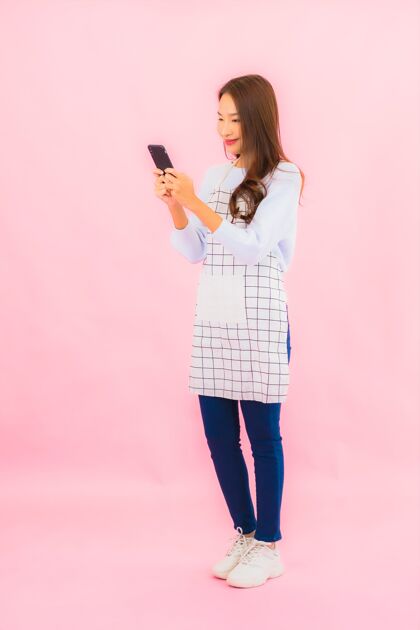 网络肖像美丽的亚洲年轻女子在粉红色的隔离墙上使用智能手机休闲工人智能手机