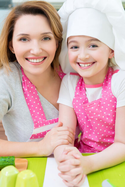 孩子厨房里穿着粉色围裙的快乐微笑的母女画像厨房健康女儿