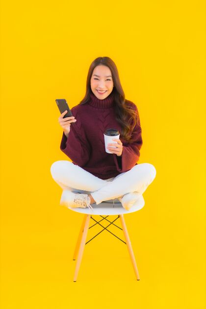 休闲肖像美丽的亚洲年轻女子在黄色背景的椅子上使用智能手机学生笔记本电脑笔记本电脑
