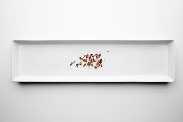 面包屑巧克力屑孤立在中心矩形陶瓷板白色桌子的背景甜点工作室拍摄抗氧化剂