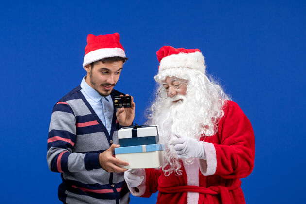 举行正面图：圣诞老人和手持礼物的年轻男性圣诞老人年轻颜色