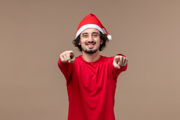 肖像正面图：棕色背景上笑脸的年轻人圣诞节男人快乐服装