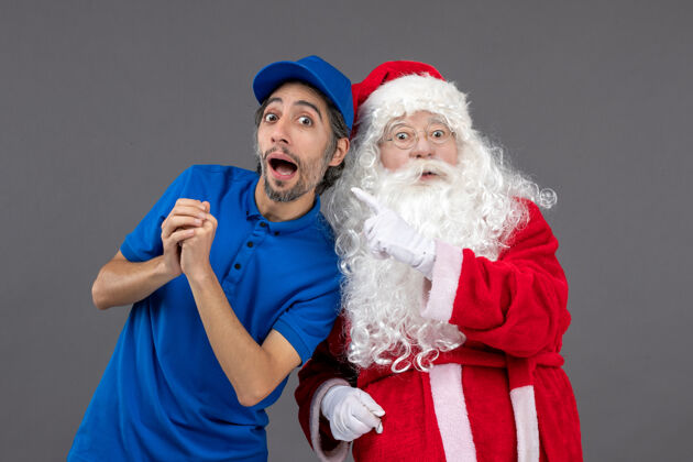 庆祝灰色墙上的圣诞老人和男信使的正面图节日信使人