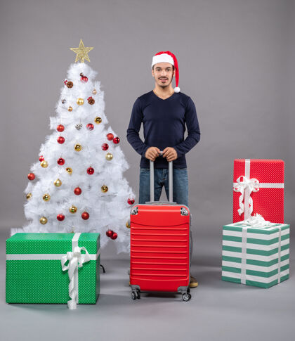 圣诞帽圣诞树旁拿着红色手提箱的圣诞老人包圣诞圣诞树