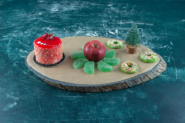 配料蛋糕 肉酱 甜甜圈和一个苹果放在蓝色的板上美味糖甜点