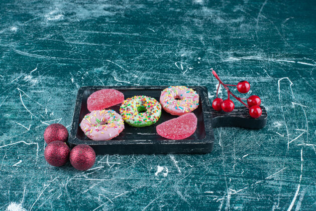 糕点在蓝色的圣诞饰品旁边的小盘子里放着甜甜圈和大理石美味美味糖果