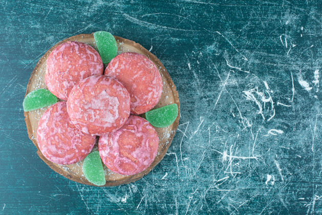甜点在蓝色的木板上涂上粉红色的饼干和marmelades美味涂层甜点