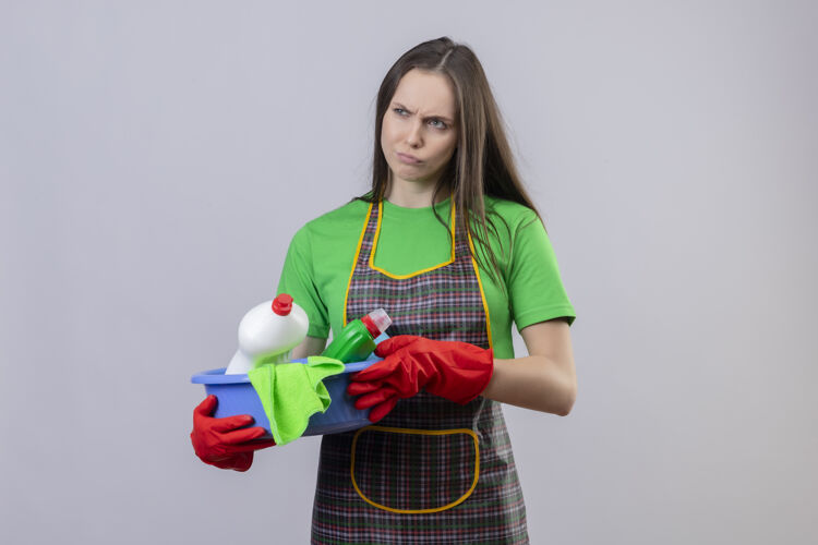 制服悲伤的清洁年轻女孩穿着制服 戴着红手套 拿着清洁工具 背景是孤立的白色清洁手套女孩