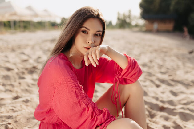 假日穿着粉色夏装的时尚现代女模特在阳光下的海滩上摆姿势年轻女人味摆姿势