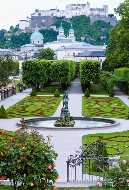 城堡米拉贝尔宫的夏季花园 后面是鲜花盛开的草坪和霍亨萨尔茨堡堡垒（奥地利萨尔茨堡）景观城市喷泉