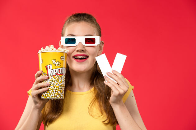 色彩正面图年轻女性在电影院里拿着爆米花和红墙电影院的票女性色彩年轻人成人视图