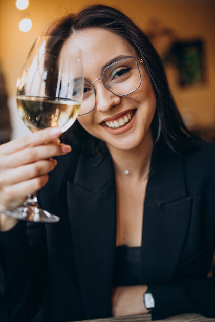 酒吧在餐馆喝白葡萄酒的年轻女子享受华丽葡萄酒