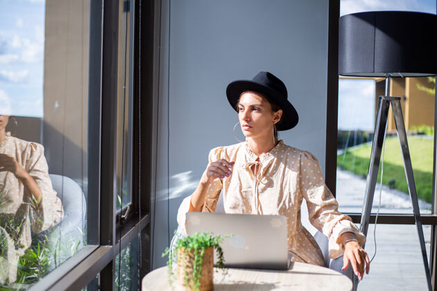 企业家穿着正装戴着经典帽子的欧洲女人在家里厨房工作热带度假体贴