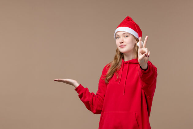 帽子前视图圣诞女孩在棕色背景上摆姿势新年圣诞节背景年份新