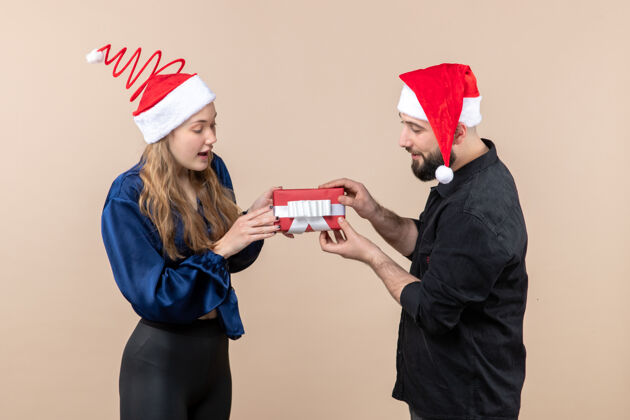 礼物年轻女子和送她礼物的男人在粉红色墙上的正视图帽子快乐圣诞快乐