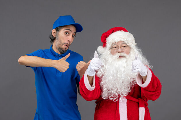 圣诞灰色墙上的圣诞老人和男信使的正面图男性节日庆祝