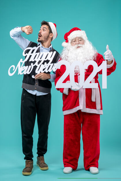 人圣诞老人的正面图 男性手持新年快乐和2021年板在蓝色墙上男人举行节日