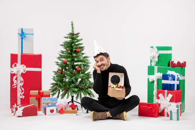 礼物正面图：年轻人围坐在白色的墙上 手里拿着圣诞礼物庆祝玩具寒冷