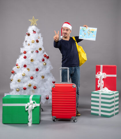 购物者欢庆的圣诞老人 背着黄色的背包 手举着灰色的胜利标志帽子礼物礼物