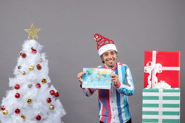 圣诞老人前视图微笑的男子与螺旋弹簧圣诞帽和条纹衬衫举行地图微笑的人快乐家伙
