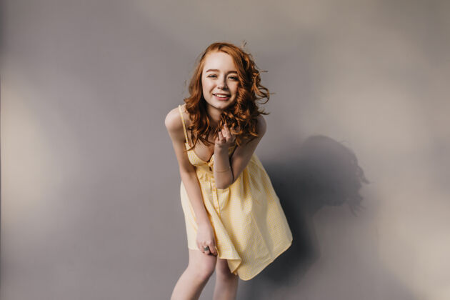 成人迷人的卷发女孩穿着时髦的黄色连衣裙笑着姜女在拍照时玩得很开心跳舞年轻姜