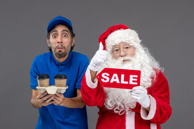 销售圣诞老人的正面图 男信使拿着售货笔 灰色墙上挂着咖啡人成人快乐