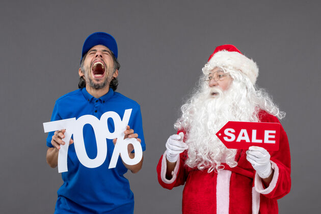 销售圣诞老人的正面图 灰色墙上的男性信使手持销售横幅吉祥物圣诞老人节日