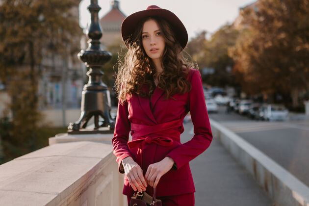 户外可爱漂亮的时尚女人穿着紫色西装走在城市的大街上 春夏秋冬时节时尚潮流戴着帽子 拿着钱包户外漂亮女士