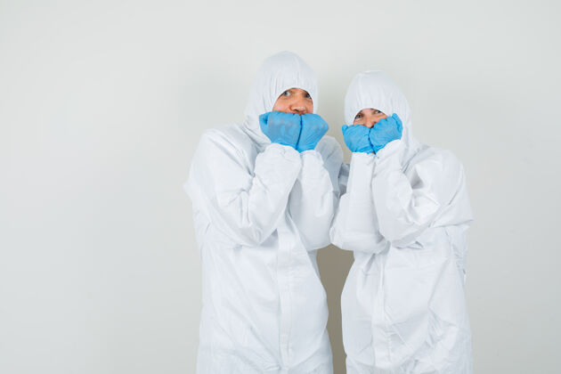 看两个医生穿着防护服 戴着手套 情绪激动地咬着拳头 看上去很害怕严重药品实验室