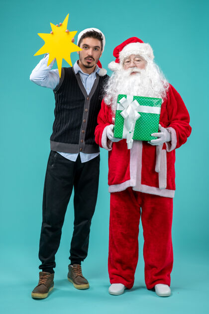 圣诞老人前视图：圣诞老人和手持蓝色背景黄色标志的年轻男性年轻男人黄色