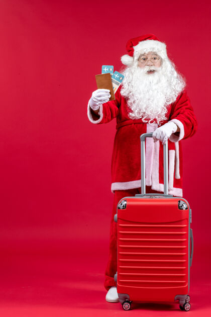 前面圣诞老人的前视图 带着包 拿着票 准备在红墙上旅行人快乐假期