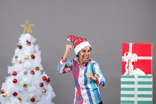 男人正面图：戴着螺旋弹簧圣诞帽的年轻人兴高采烈地展示着他的幸福帽子年轻兴高采烈