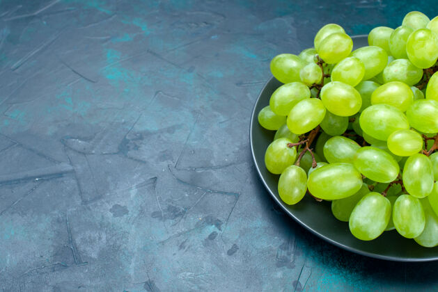 葡萄在浅蓝色的桌子上近距离观赏新鲜的绿色葡萄 多汁和醇厚的水果醋栗水果前面