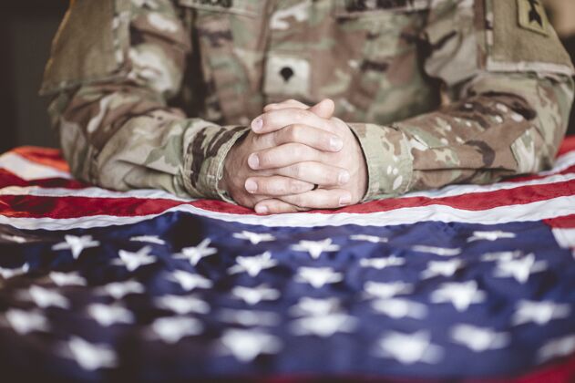 团结美国士兵在他面前举着美国国旗哀悼和祈祷爱国者旗帜部队