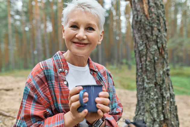 饮料可爱的幸福的欧洲女性退休人员与金发在户外露营地休息的看法远足可爱杯子
