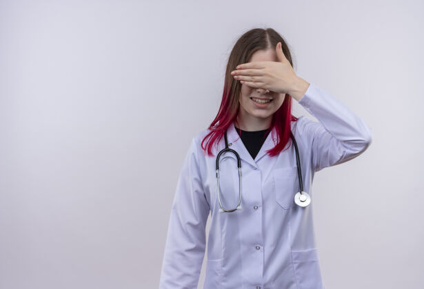 长袍微笑的年轻女医生穿着听诊器医用长袍 手捂着眼睛 背景是白色的 有复印空间复制封面空间