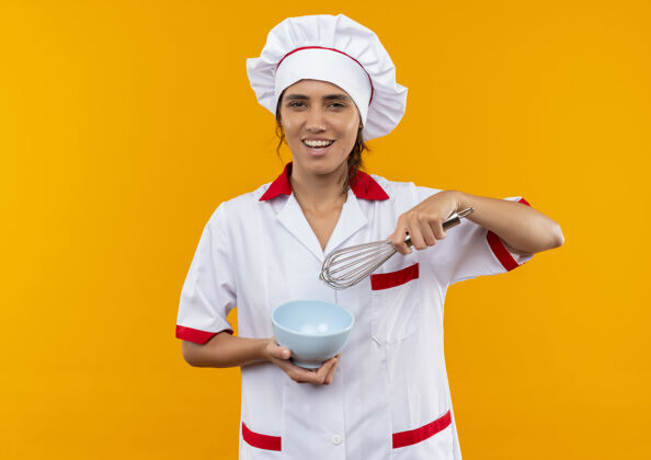 拿着面带微笑的年轻女厨师穿着厨师制服拿着打蛋器和碗 有复印空间厨师制服厨师