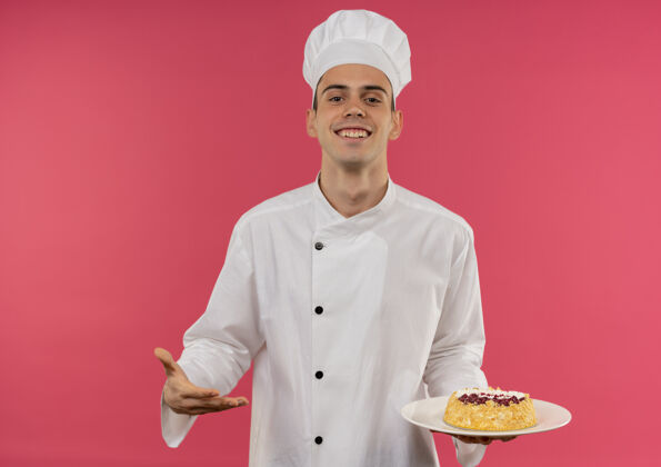 分面带微笑的年轻男厨师身穿厨师制服 手拿蛋糕点着盘子盘子男戴着