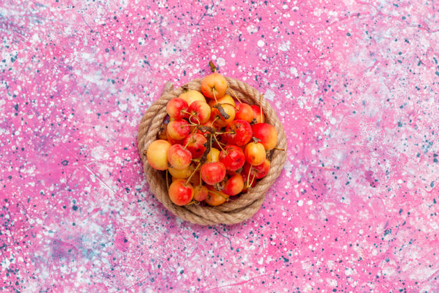 绳索在粉色背景上用绳子顶着新鲜的甜樱桃新鲜水果种子