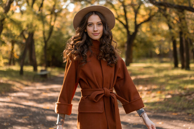 波西米亚迷人时尚微笑的瘦身女子卷发漫步公园身着暖棕色外套 秋日时尚街头风夹克时尚漂亮
