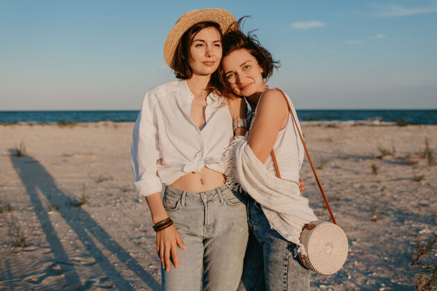 取向两个年轻女子在日落海滩上玩得很开心 男女同性恋爱情浪漫女同性恋拥抱微笑